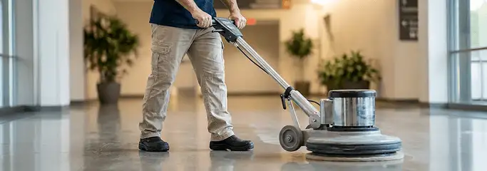 Professional technician using an industrial floor buffer to polish and maintain shiny commercial flooring in a corporate hallway in Erie, PA.
