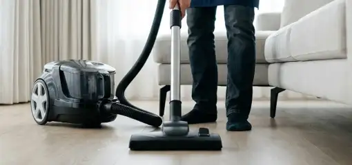 Professional house cleaner vacuuming a living room floor with a canister vacuum cleaner, Erie, PA.
