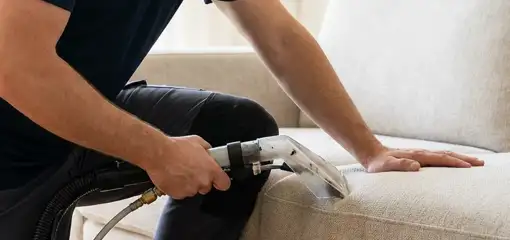 Professional upholstery cleaner deep-cleaning a fabric sofa with a handheld extraction tool, Erie, PA.